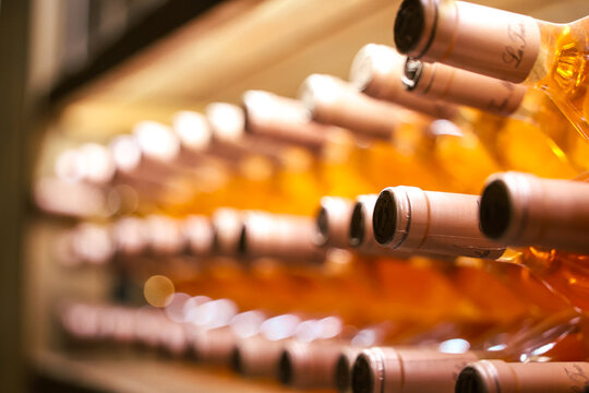  Rows of sealed bottles of rose wine rest in a dimly lit cellar, showcasing elegant storage and timeless craftsmanship. Perfect for themes of luxury, tradition, and fine wine making.