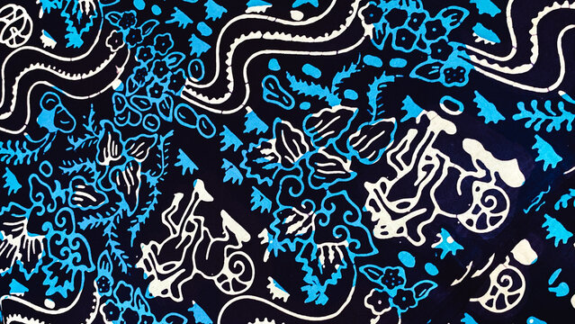 Close up texture of black and blue Indonesian batik fabric featuring traditional floral and horse cart carriage motif.