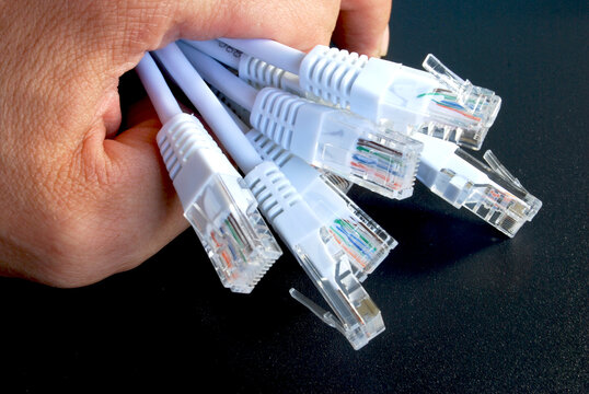 male hand holding a bunch of plugs with RJ45 connector from a white ethernet network cable
