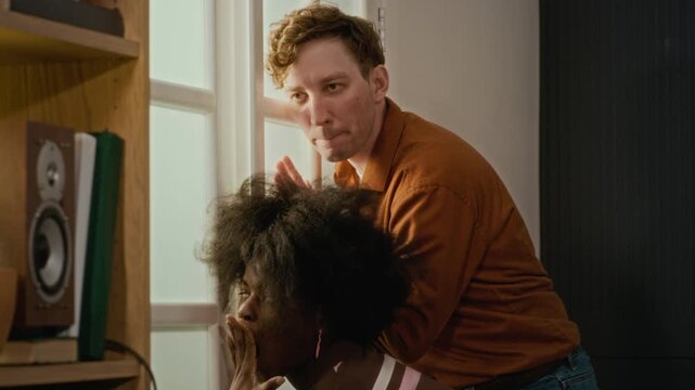 Young African American woman and two young Caucasian men peeking curiously through glass door. Perfect for comedy ads, neighborly gossip concepts, or funny storytelling videos