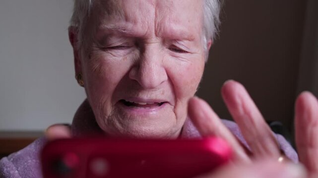 Senior woman with presbyopia and poor vision struggling to read her mobile phone, squinting her eyes to see the small text on the screen, representing common eyesight problems in old age