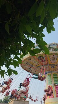 Visitors of the amusement park are enjoying the wave swinger ride. Visitors are excited to try the swing ride at the amusement park