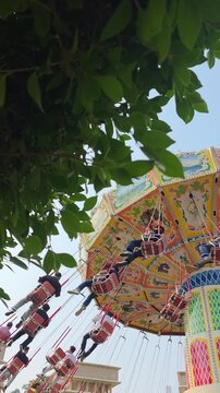 Visitors of the amusement park are enjoying the wave swinger ride. Visitors are excited to try the swing ride at the amusement park