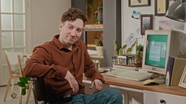 Medium portrait of Caucasian young man typing on retro computer, turning to smile at camera. Clip is perfect for vintage technology marketing or nostalgic IT history videos