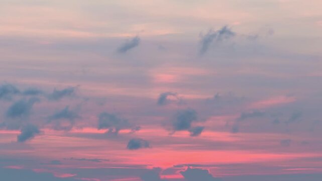 Pink and blue sky at sunset at the beach with slow moving purple clouds