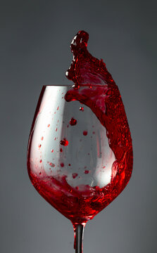 An image of red wine being splashed into a glass.