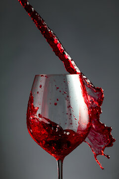 An image of red wine being splashed into a glass.