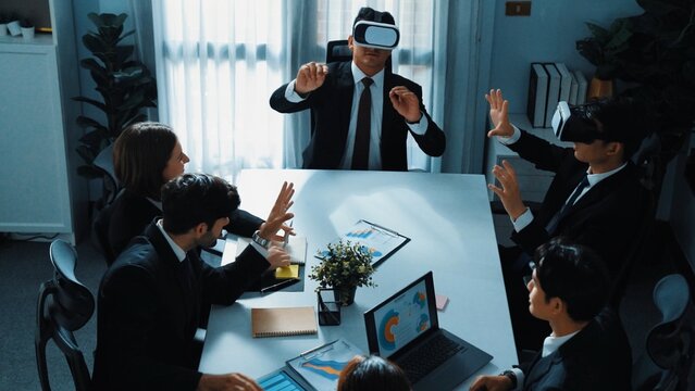 Top view of manager working on laptop and sending data analysis to business people by using VR glass headset while diverse team planning marketing strategy and looking at financial graph. Directorate.