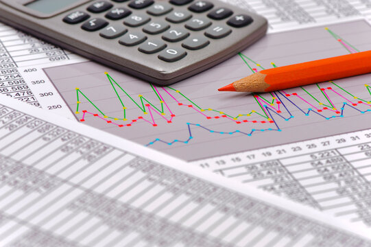 Ein Stift liegt auf Tabellen mit vielen Zahlen  zur finanziellen Statistik und Berechnung mit einem Chart