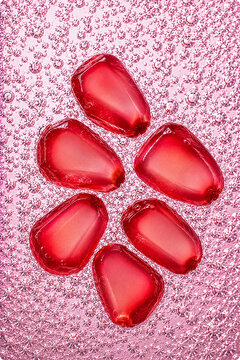 Fresh pomegranate arils surrounded by sparkling bubbles in a vibrant macro composition. Bright healthy food background with refreshing texture.