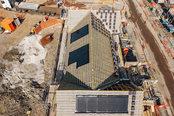 Naklejka premium Construction of a new building with solar panels on the roof seen from above in an urban area