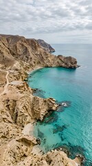 Fototapeta premium Aerial View of Rugged Desert Cliffs Meeting Turquoise Ocean Waters Along Arid Coastal Shoreline