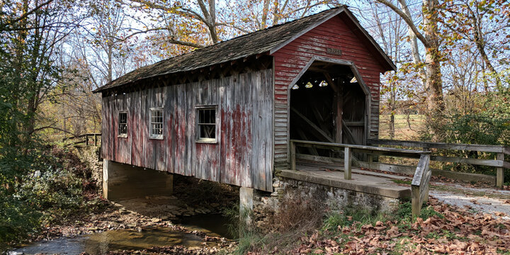 Rustic Wooden Covered Bridge Over a Shallow Stream with Fall Foliage