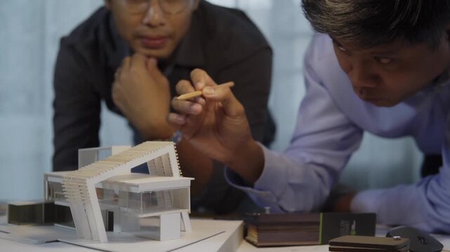 Architects discuss building modern house scale model in office. Team collaborates closely. concept of architectural design, residential property design process, real estate project planning.