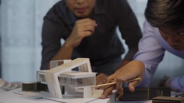 Architects discuss building modern house scale model in office. Team collaborates closely. concept of architectural design, residential property design process, real estate project planning.