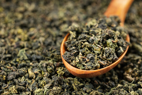 Tieguanyin loose leaf in wooden spoon on solid background