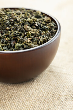 Macro overhead shot premium loose tea in wooden cup on linen like fabric