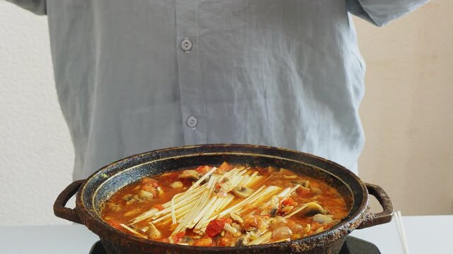 Vegetables with meat and udon are stewed in a frying pan in Pad Thai sauce and spices, boiling and bubbling. Medium plan.