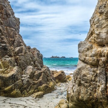 Exploring the rocky coastline of Crozon in Bretagne and admiring the distant island under a cloudy sky