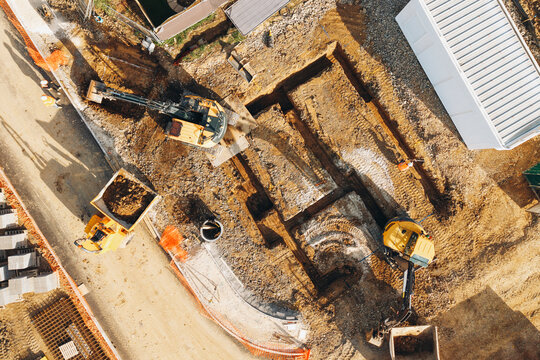 Construction site showing excavation work in progress during daylight hours with machinery and earth moving vehicles