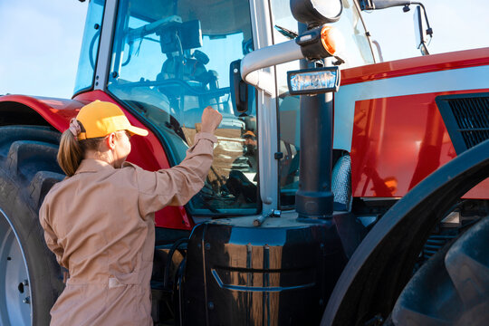Worker prepares to start a red tractor on a sunny day at a farm