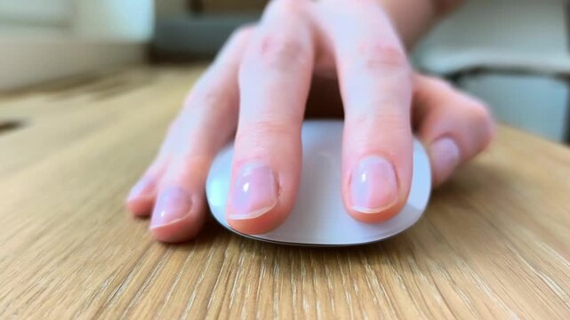 Hand clicking a computer mouse during everyday work. Fingers pressing the button in a close-up office scene. Detailed view of digital navigation at a desk..