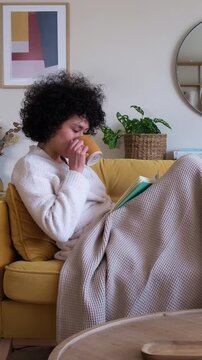 Young woman enjoying coffee while reading on a cozy sofa
