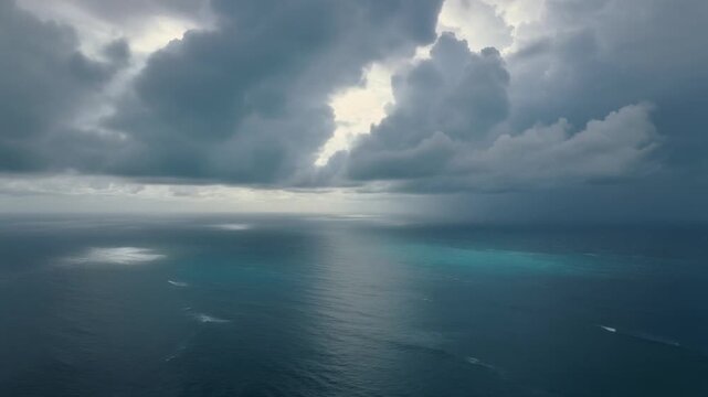 Cinematic drone footage above the ocean beneath towering tropical storm clouds