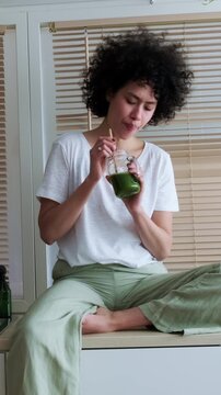 Disgusted woman drinking a healthy green detox smoothie