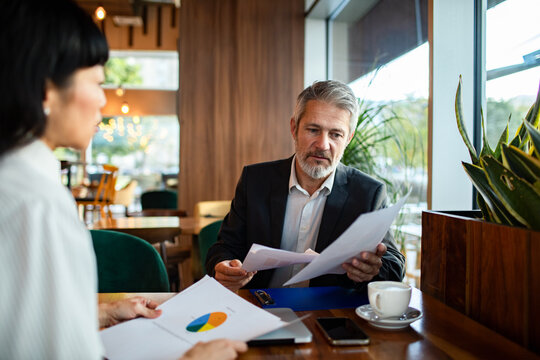 Business colleagues reviewing financial reports in cafe