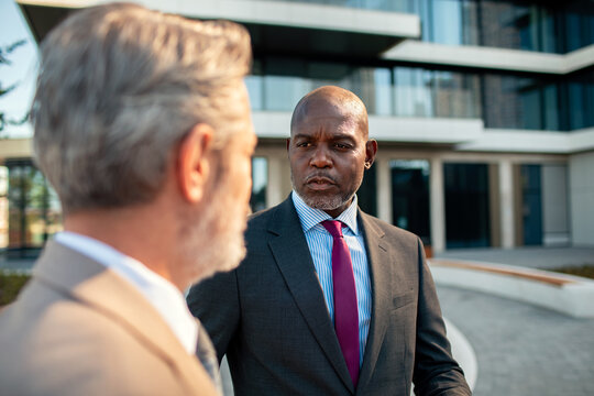 Two business executives discussing strategy outside modern office