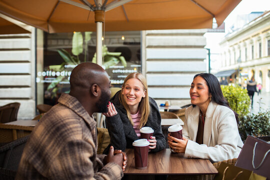 Friends chatting over coffee at outdoor cafe terrace