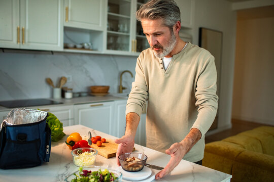 Middle-aged man weighing ingredients on a kitchen scale at home