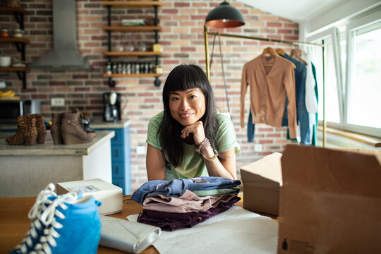 Woman entrepreneur packing clothing orders in home kitchen