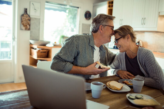 Happy senior couple sharing breakfast at home kitchen table