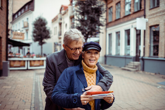 Senior couple sightseeing with map on european city street