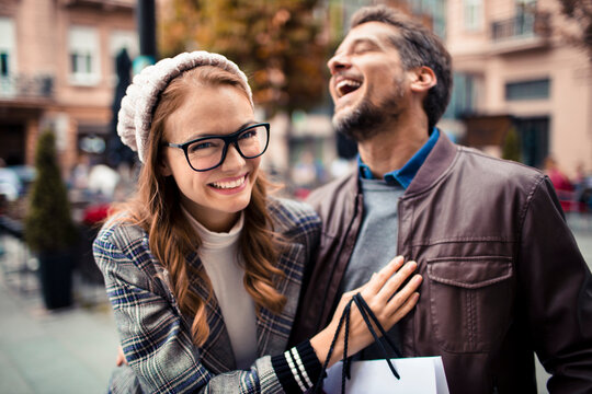 Smiling friends laughing while shopping on city street
