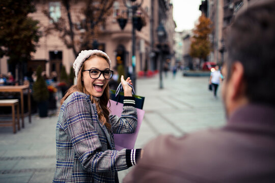 Cheerful woman with shopping bags on city street in autumn