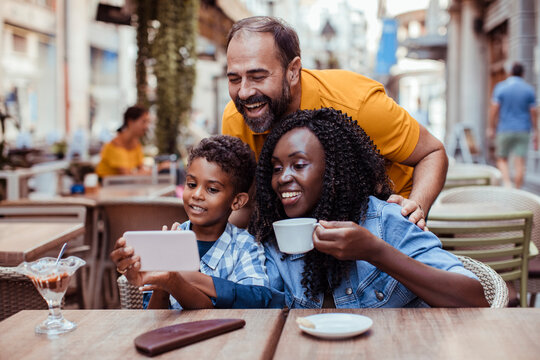 Happy family taking selfie at outdoor cafe