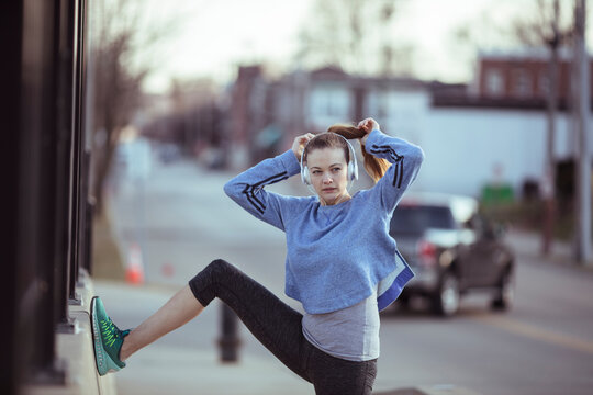 Young woman stretching on urban sidewalk before run