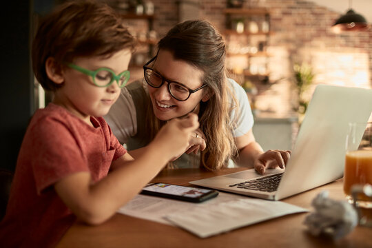 Mother helping child with online learning at home kitchen