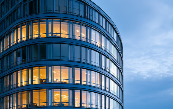 Modern Glass Office Building Exterior with Illuminated Windows Reflecting Dusk Sky