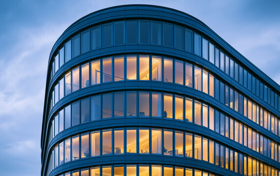 Modern Glass Office Building Exterior with Illuminated Windows Reflecting Dusk Sky