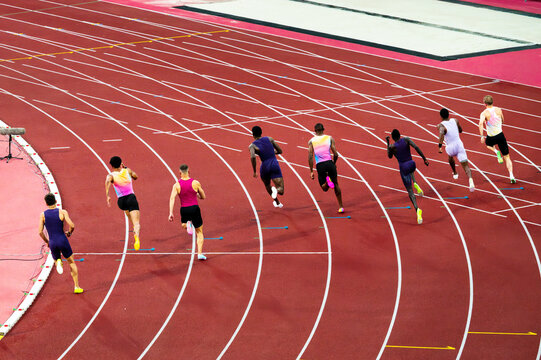 Sprinters racing on an athletics track. Muscular world-class male athletes compete in a professional 200 m sprint race. Illustrative photo of sprinting and track and field.