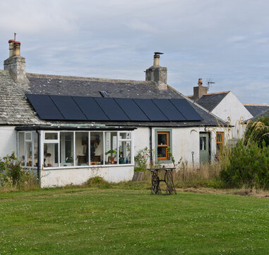 Solar panels on a stone cottage in Kingston, Moray, Scotland during the day