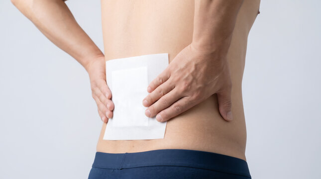 突然のぎっくり腰や腰痛で腰に湿布を貼る男性・応急処置と湿布薬
