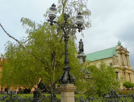 Poland, Warsaw, 25 Krakowskie Przedmieście, forged street lamp against the background of the monument to Mickiewicz