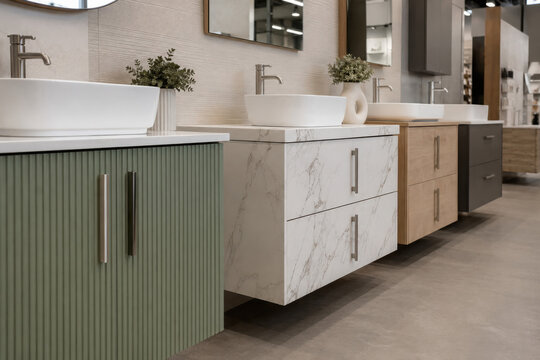 Modern bathroom vanity cabinets and washbasins displayed in a showroom interior. Contemporary bathroom furniture, interior design solutions, home renovation and sanitary ware for retail.