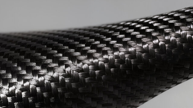 Macro photography of black carbon fiber texture with woven composite pattern and light reflection