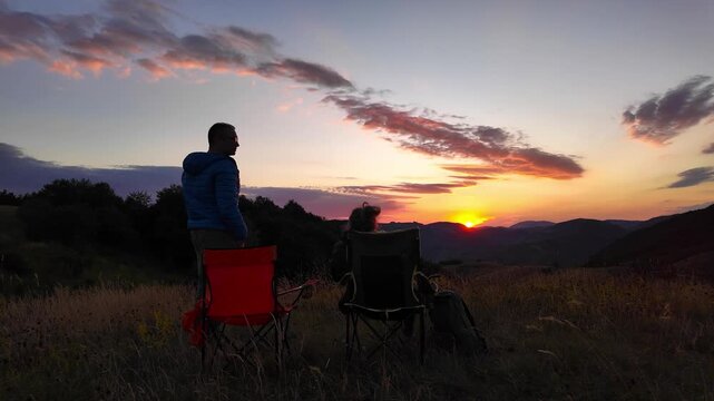 Man and woman looking at the sunset over the distant mountains.